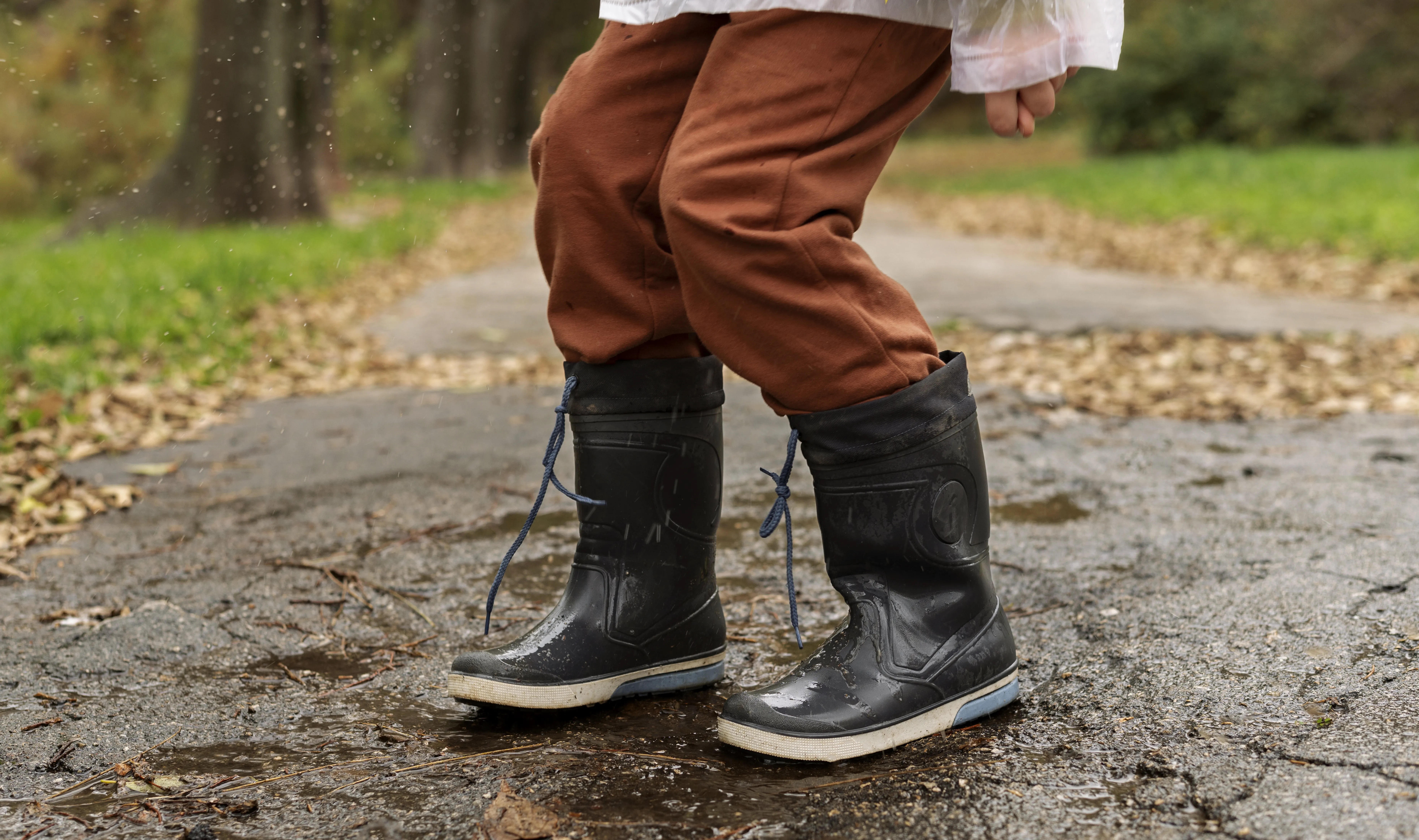 Child wearing muddy boots standing in a puddle, illustrating the need for a mudroom to contain dirt and outdoor messes