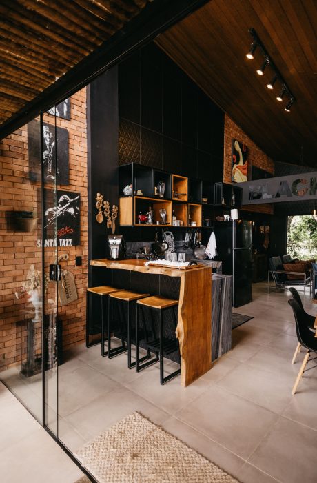 Go bold with a moody speakeasy vibe. This custom home bar design pairs dramatic matte black storage and a live-edge countertop with large-format floor tiles for a flawless, high-contrast entertainment hub.